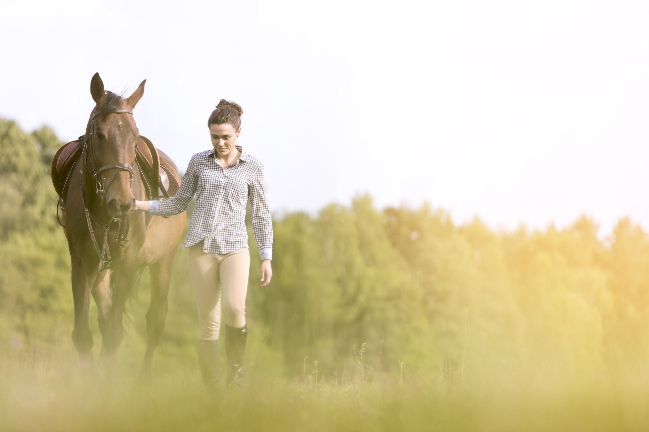 Woman walking horse in rural field